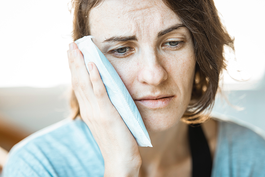 A close-up image of a person holding their ear in pain