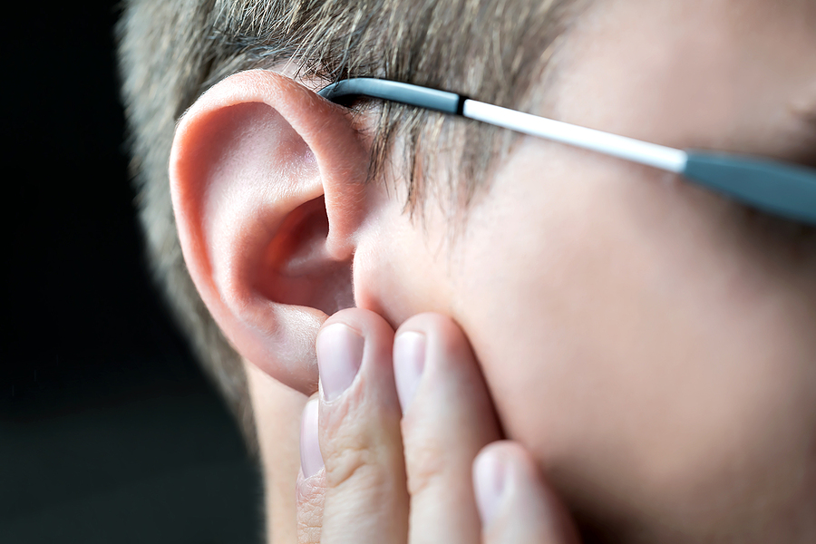 A person holding their ear with a concerned expression