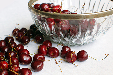 A close-up image of a pile of fresh cherries