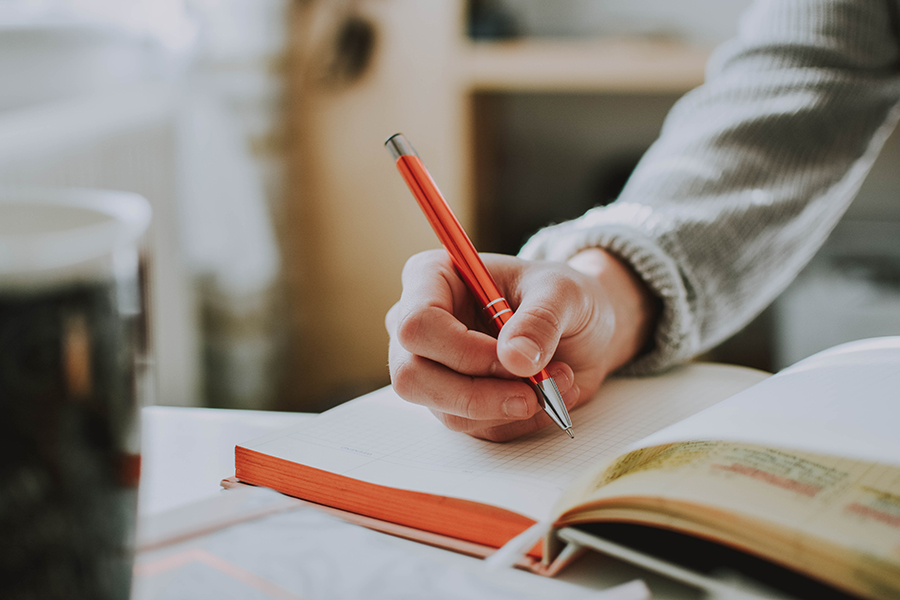 A person writing in a journal as a form of stress relief and to improve mental health.