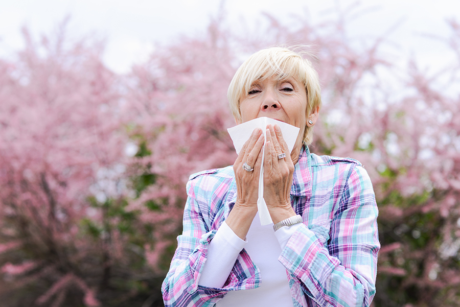 Image of person wearing earplugs to protect ears during allergy season and prevent hearing loss.