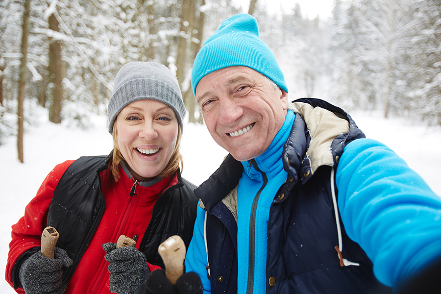 A person wearing earmuffs in the snow to protect their hearing from the cold weather and prevent hearing loss.