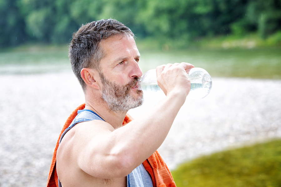 A person staying hydrated while exercising in the heat to prevent heat-related illnesses.