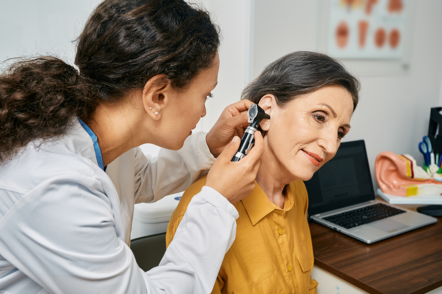 Audiologist examining patient's ear for signs of hearing loss.