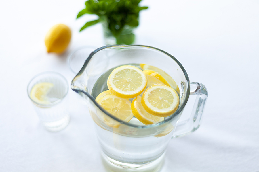 A person holding a glass of water with lemon slices