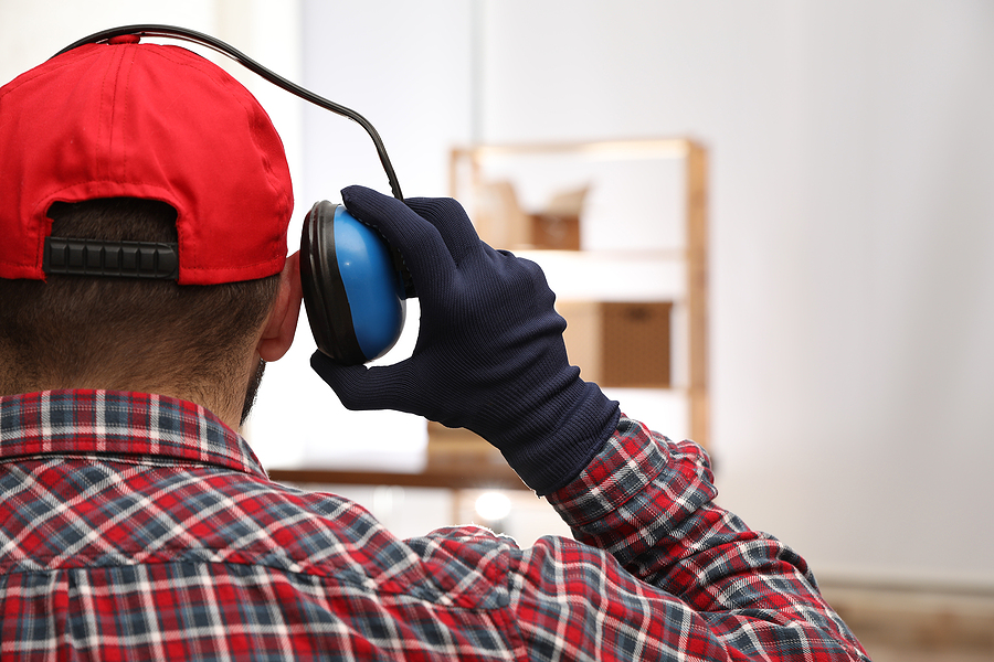 Image of person wearing earplugs in a noisy environment to prevent hearing loss and protect their hearing health.